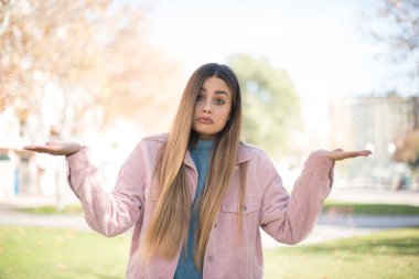 Kafası karışmış, kolları açık, omuzlarını silkip: 