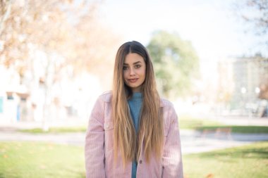 Güven ve iş kavramı. Pembe ceketli, kendine güvenen bir ifadeyle gülümseyen çekici sarışın kadın portresi.