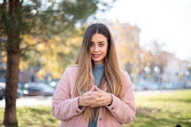 Parkta pembe ceketli güzel sarışın kadın.  