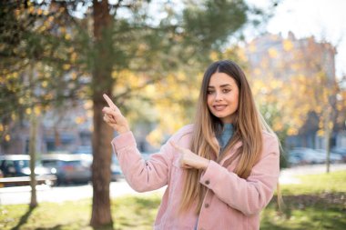 Pembe ceket giyen, ağzı açık, neşeli bir yüz ifadesi olan çekici, genç bir kadın, dışarıda inanılmaz bir şey gösteriyor. Reklam kavramı