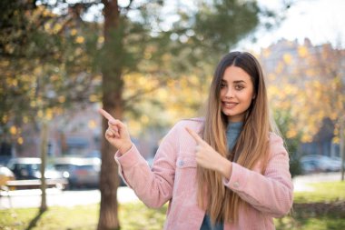 Yeşil gözlü pembe ceketli, çekici, genç, çekici bir kadın. Ağzı açık, neşeli bir yüz ifadesi olan, açık havada inanılmaz bir şey gösteriyor. Reklam kavramı