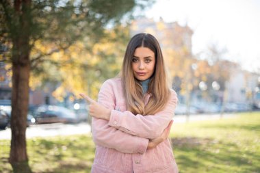 Olumlu ve çekici genç bir kadın, ağzı açık neşeli ve gülümseyen bir yüz ifadesiyle açık havada inanılmaz bir şey gösteriyor. Reklam kavramı.