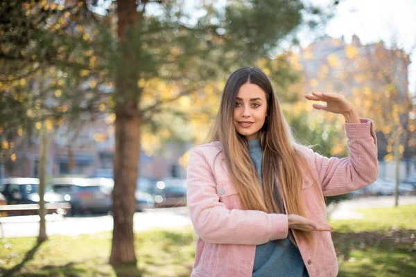 Pembe Ceketli Güzel Sarışın Kadın Parkta Bir Şey Gösteriyor — Stok fotoğraf