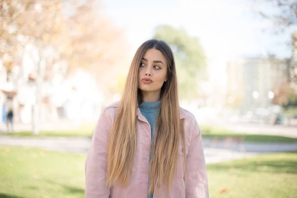 Genç Güzel Sarışın Pembe Ceketli Bir Kadın Parka Bakıyor — Stok fotoğraf