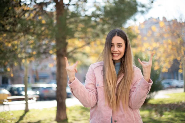Bu dünyayı sallamak için doğmuşum. Moda kıyafetleri içinde neşeli bir kadın yüksek sesle bağırıyor ve kollarını kaldırmış kornalarla ya da rock hareketleriyle gösteriyor. Konserde olmanın heyecanını dile getiriyor. Dışarıda dikiliyorum