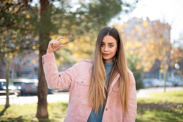 Pembe Ceketli Güzel Sarışın Kadın Parkta Bir Şeyler Gösteriyor — Stok fotoğraf