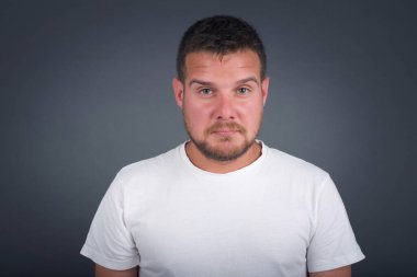 Üzgün bir adamın, hüzünlü bir yüz ifadesi ve duygu konseptiyle gri arka planda izole edilmiş acı ve depresyondan muzdarip gözlerinde yaşlarla umutsuz ve depresif bir şekilde ağlayan güzel yüzü..