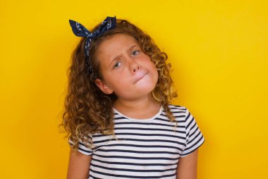 Düşüncelere dalmış, kaşlarını kaldırıyor, dudaklarını kıvırıyor, şık kıyafetler giyiyor.