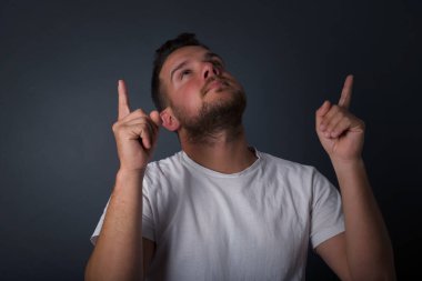 Parlak makyajlı, parlak görünümlü, her iki işaret parmağını havaya kaldırıp boş bir fotokopi duvarında şok edici bir şey gösteren başarılı bir genç adamın yatay görüntüsü..