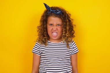 Vücut dili. Gri duvara karşı poz veren, suratını asan, bir şeyden tiksindiğini gösteren, stresli, güzel bir kız..