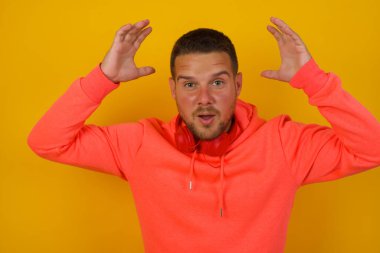 Genç yakışıklı adamın sarı duvara karşı kafası karışmış. 