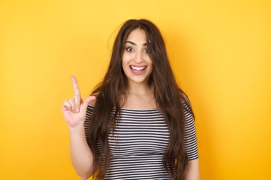 Hoş görünümlü genç kadın modelin yakın portresi zekice bir ifadeye sahiptir, bir parmağını kaldırır, önemli bir şeyi söylemeyi unutmaması gerektiğini hatırlar. Kapalı