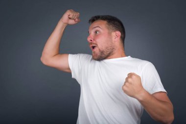 Çekici beyaz adam zaferi kutluyor yumruklarıyla havaya yumruk atıyor ve stüdyo arka planında fotokopi aletiyle ışıldayan dişli bir gülümsemesi var..