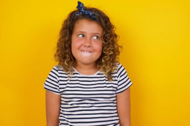 Düşünceli bir yüzü olan, ellerini aşağıda tutan dudaklarını ısıran tatlı bir şey düşünen hayalperest bir kız. 