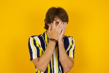 Endişe - güzel bir beyaz adamın kavramsal görüntüsüdür. Ellerini yüzünü kapatır ve parmaklarının arasından dışarı bakar. Bir şeyden ya da birinden korktun mu?.