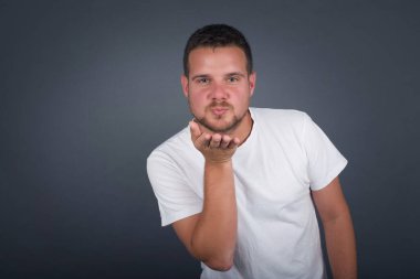 Sevimli çekici erkek kameraya yumruk atar, sevgilisine aşkını gösterir ya da uzaktan veda eder, beyaz stüdyo arka planında izole bir şekilde. Çekici genç adam birine sempati gösterir..