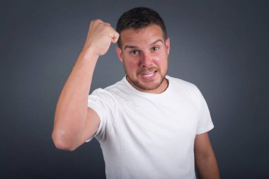 Vahşi, kendine güvenen, Avrupalı, koyu renk saçlı bir adam. Önünde yumruğunu tutuyor. Sanki dövüşmeye ya da meydan okumaya hazırmış gibi. Gri arkaplan üzerinde izole.