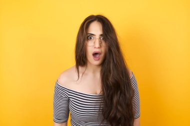 Çekici genç bir kadın ağzı açık, ağzı açık, ağzı açık bir şekilde şoke olmuş bir şekilde arkadaşının hikayesini dinlerken 