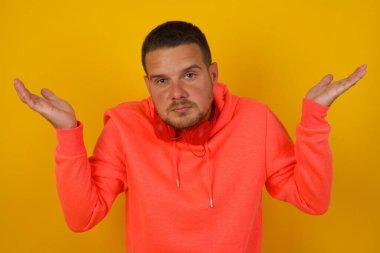 Genç yakışıklı adamın sarı duvara karşı kafası karışmış. 