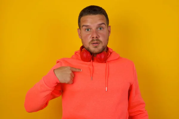 Young handsome  man     pointing himself  against yellow  wall