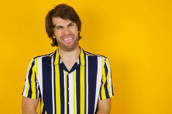 Body language. Disgusted stressed out pretty man posing against gray wall, frowning his face, demonstrating aversion to something.