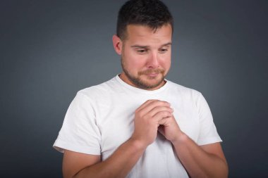 Üzgün, hoş bir adam evde yalnız başına vakit geçirirken üzgün hissediyor. Yakışıklı, genç, sarışın erkek. Mutsuz ve üzgün bir şekilde kameraya bakıyor. Kapalı alanda duruyor..