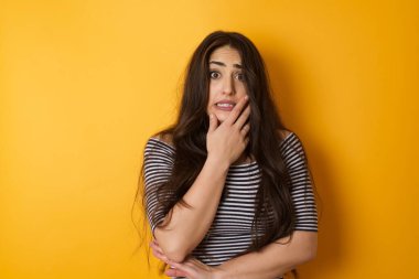 Endişe. Güzel, genç, beyaz bir kadının kavramsal bir görüntüsü. Uzun saçlı, ağzı kapalı ve kapalı bir yerde duran bir kadın. Bir şeyden ya da birinden tırnak yemekten korktun mu?