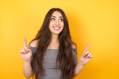 Başarılı, dost canlısı, parlak makyajlı, parlak saçlı bir kadının işaret parmağıyla işaret ederek boş bir fotokopi duvarında şok edici bir şey gösterdiği yatay bir görüntü..