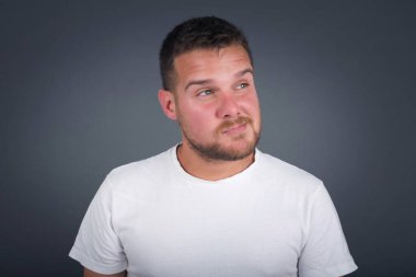 Düşüncelere dalan, kaşlarını kaldıran, dudaklarını kıvıran, şık kıyafetler giyen, metnin için fotokopi alanı olan gri duvara karşı duran düşünceli çekici bir adam..