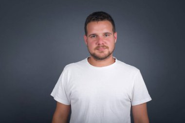 Hoş görünümlü beyaz bir adamın yatay portresi. Günlük kıyafetler giymiş, kameraya mutlu bir şekilde bakıyor..