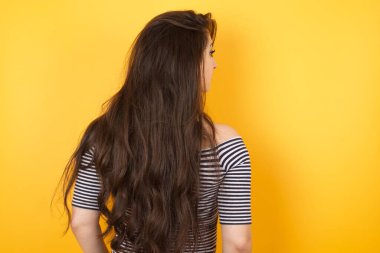 Duvarda duran uzun dalgalı ve parlak saçlı bir kızın arka tarafı. Stüdyo Çekimi. 