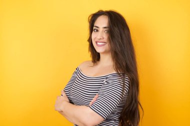 İçerde kollarını kavuşturmuş neşeli beyaz bir kadının görüntüsü. Kameraya bakıp gülümsüyor. Kendine güvenen kız..