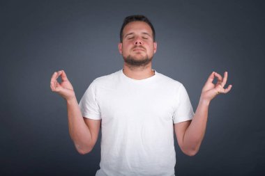 Meditasyon, din ve ruhani uygulamalar. Yakışıklı genç adam sabah uyandıktan sonra evde yoga yapıyor, gözlerini kapalı tutuyor, parmaklarını Mudra jestinde tutuyor..