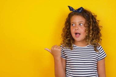 Omg konsepti. Şaşırmış beyaz kız, şaşırmış bir ifadeyle, gözlerini ve ağzını iyice açıyor, başparmağıyla işaret ediyor, garip bir şey gösteriyor. 