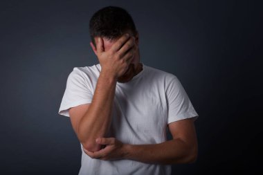 Havalı saç kesimi olan yakışıklı bir adamın kapalı bir portresi, günlük kıyafetler giyen, gülümseyen bir avuç içi hareketi yapan, gri arka planda duran aptal duruma şaşırmış..    