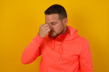 Sarı duvarda baş ağrısı olan yakışıklı bir genç. 