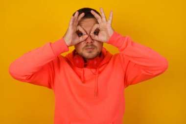 Genç yakışıklı adam sarı duvara gözlük yapıyor. 