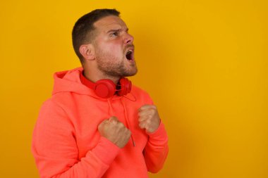 Genç adam sarı duvara bağırıyor. 