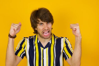 Güçlü, kararlı, genç bir erkeğin portresi. Kollarını kaldırıyor, yumruklarını sıkıyor, sevinç ve heyecanla haykırıyor. Zafer, başarı ve başarı kavramı.