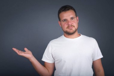 Pozitif memnun adam der ki: Vay be, ne kadar heyecan verici, hayret verici bir ifade, boş uzayda bir şey gösteriyor, açık elle izole edilmiş gri arkaplan üzerinde. Reklam kavramı.
