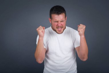 Kafkasyalı esmer adam başarısını ve zaferini sevinçle kutluyor ve yumruklarını zevkle sıkıyor. Hedefine ve hedeflerine ulaşmaktan mutlu olan şanslı bir adam. Olumlu duygular, duygular.