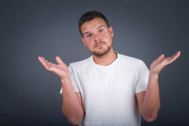 Kafası karışmış, kolları açık, omuzlarını silkip 