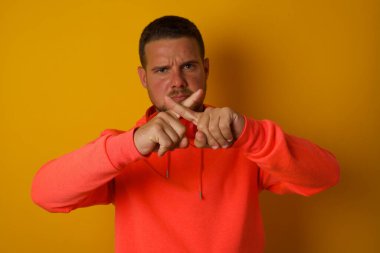 Sarı duvara karşı jest yapmayan genç yakışıklı adam. 