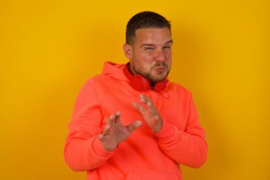 Genç yakışıklı adam sarı duvardan korkuyor. 