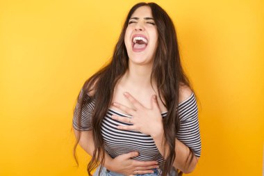 Neşeli Avrupalı öğrenci güzel şakalara güler, günlük kıyafetler giyer uzun saçlı mutlu genç kadın