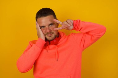 Sarı duvarda el kol hareketi yapan genç yakışıklı adam. 