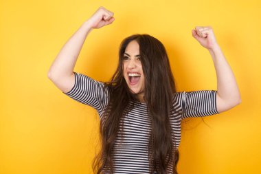 Evet, ben kazandım. Çekici, keyifli ve heyecanlı beyaz kadın portresi. Uzun saçlı, yumruğunu zafer ve zaferle kaldırıyor. Mutluluktan sırıtarak başarı elde ediyor..