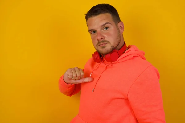 Young   man  pointing himself    against yellow  wall