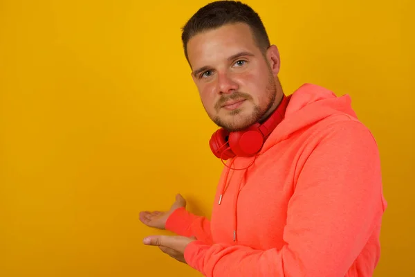 Young handsome  man showing something    against yellow  wall