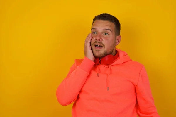 Young handsome  man  is confused  against yellow  wall